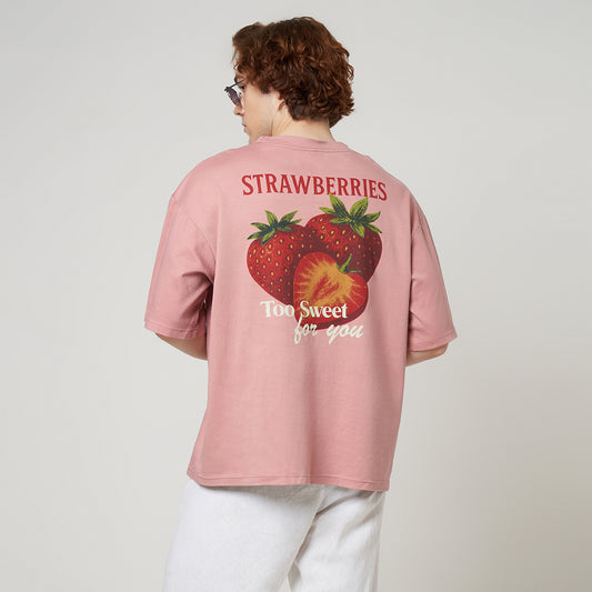 Back view of a dusty pink oversized tee featuring a vintage-style strawberry graphic print with "Strawberries Too Sweet For You" text.