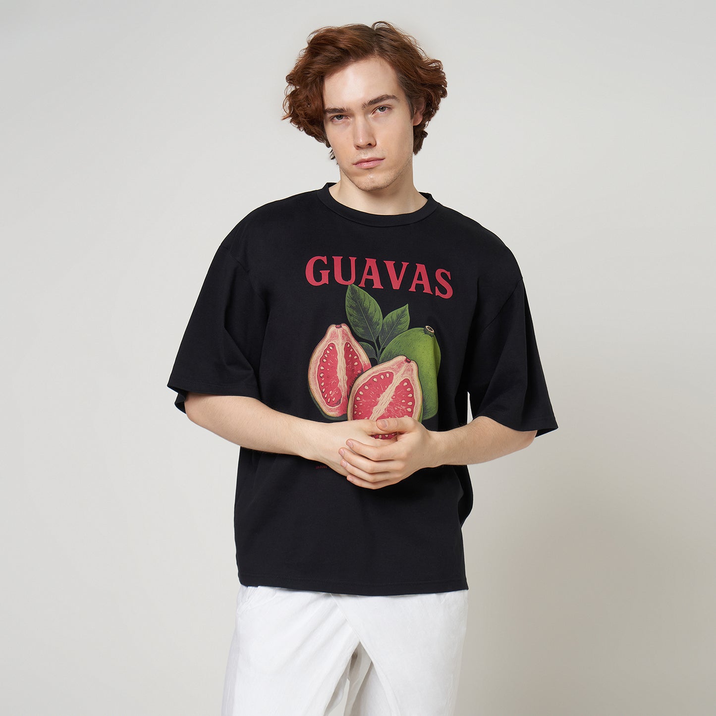Male model wearing the VERBO Guavas Boxy Oversized Tee in Noir black with white wrap-style trousers.