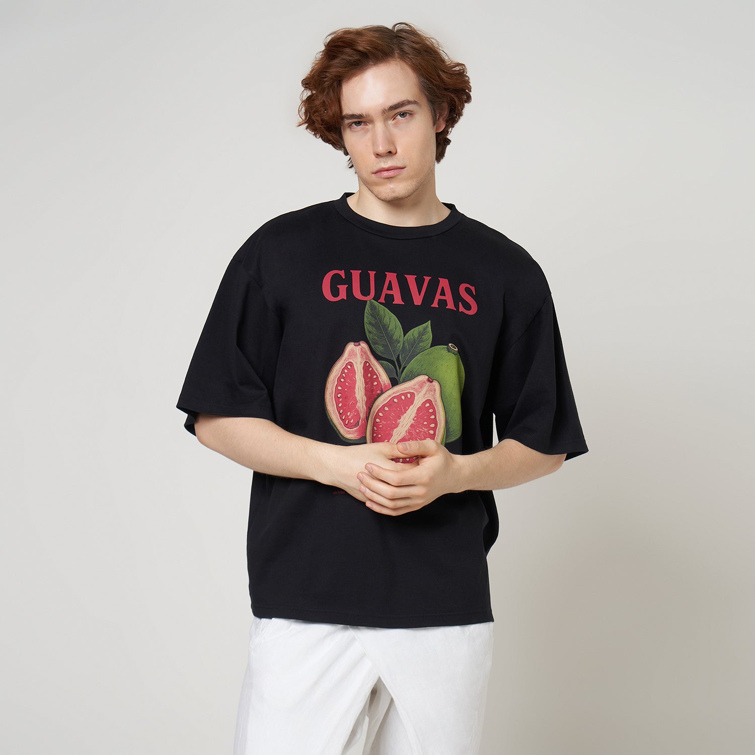 Male model wearing the VERBO Guavas Boxy Oversized Tee in Noir black with white wrap-style trousers.