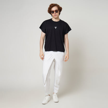 Male model wearing the VERBO Noir black cropped tank with white linen trousers for a modern minimalist streetwear look.
