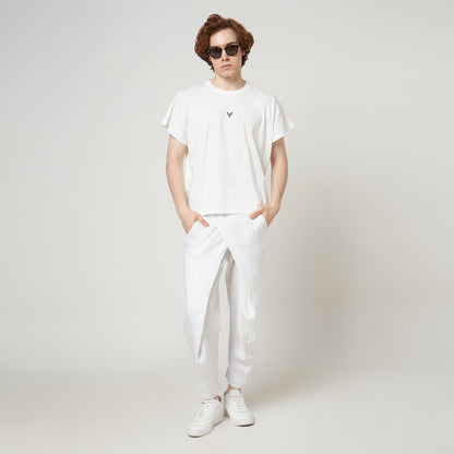 Male model wearing the VERBO white cropped tank with white linen trousers for a modern minimalist streetwear look.