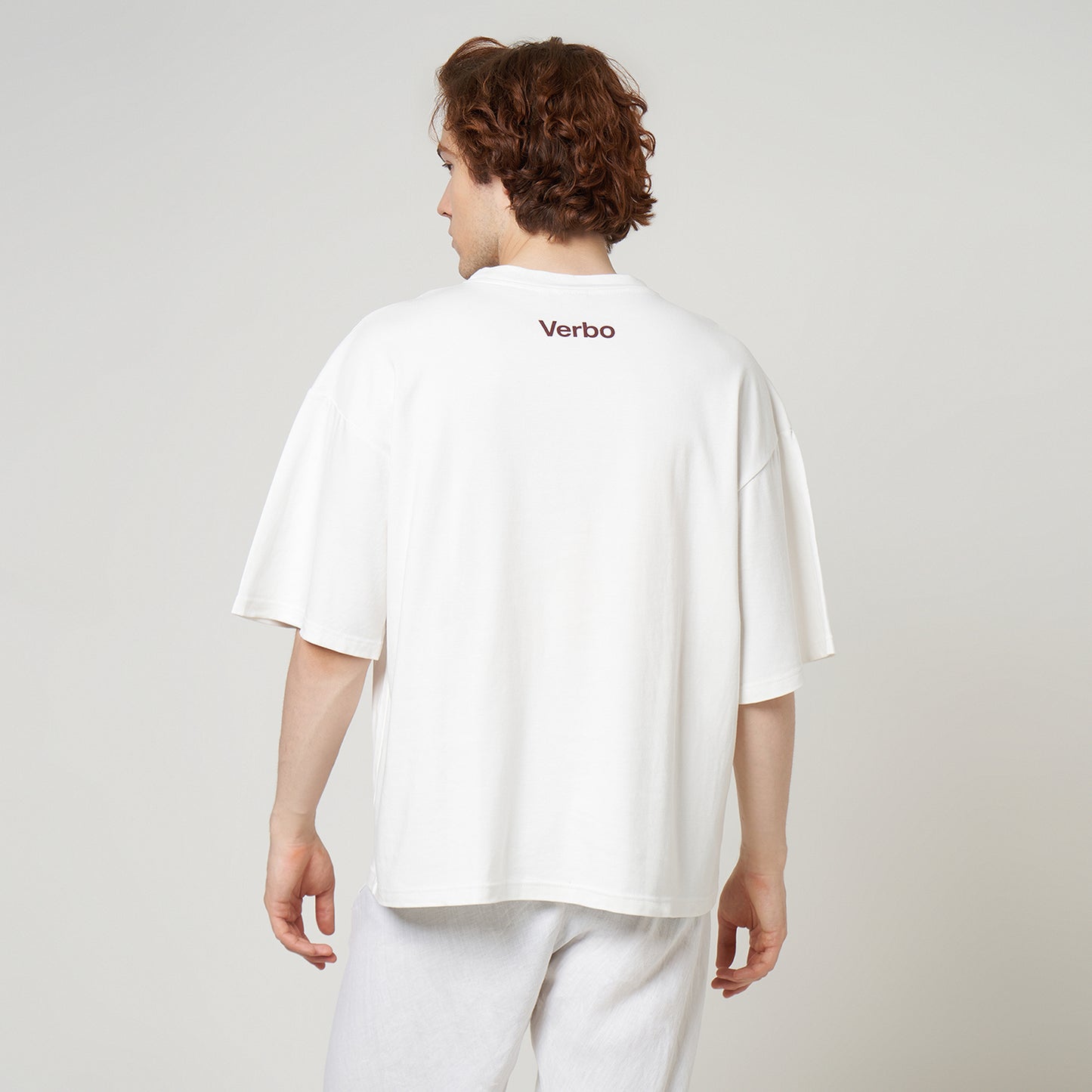 Model showcasing the wide, oversized fit and back branding of the VERBO Broken White Apple Tee.