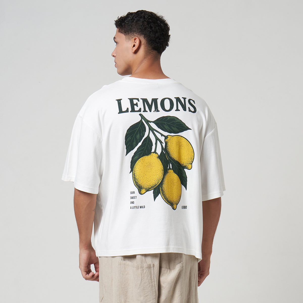 model wearing a broken white oversized tee with lemon graphic and 'LEMONS' text on the back.