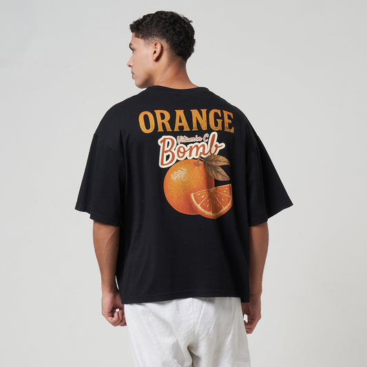 Rear view of the Noir black boxy tee on a model, showcasing the large orange "Vitamin C Bomb" back graphic.