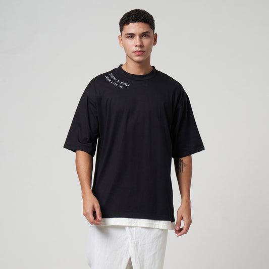Model wearing the VERBO Inspired to Begin Layer Tee in Noir, showing the layered hem design and relaxed fit.