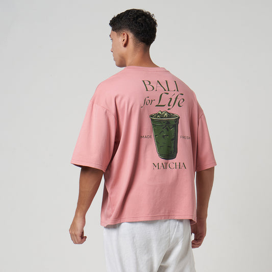 Rear view of a model showcasing the oversized fit and "Bali For Life" matcha latte graphic of the Rose Tan Verbo tee.